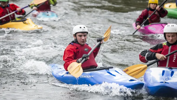 Students in canoes navigating a small rapids. 