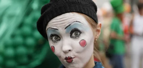 Close up of lady made up as a clown, wearing a woollen beret. 