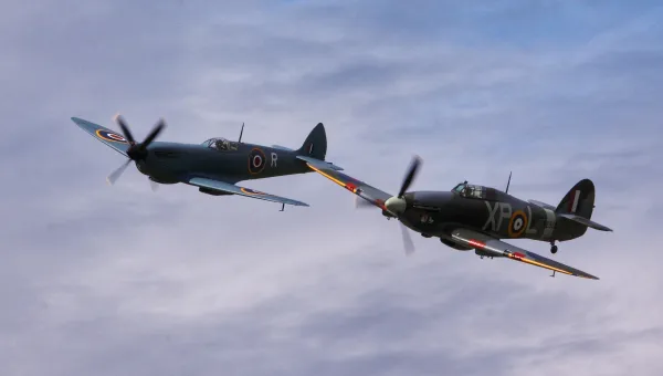 A Spitfire and a Hurricane flying in blue sky.