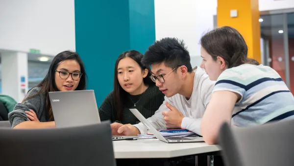 Group of animated students looking at a laptop.