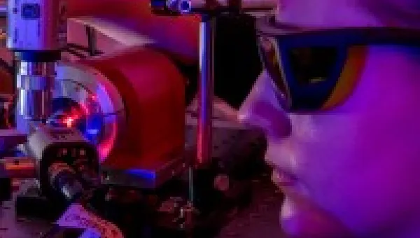 Female photonics degree student wearing glasses and staring into machine