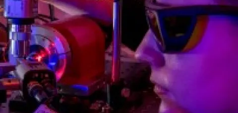 Female photonics degree student wearing glasses and staring into machine