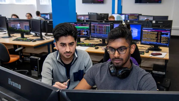 Student and tutor looking at business trading screen.