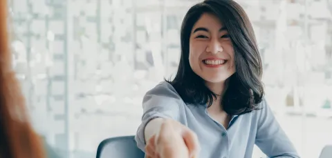 Women shaking hands over a desk