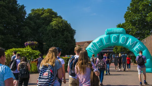 Open Day visitors walking through a large, blue welcome archway at Highfield Campus