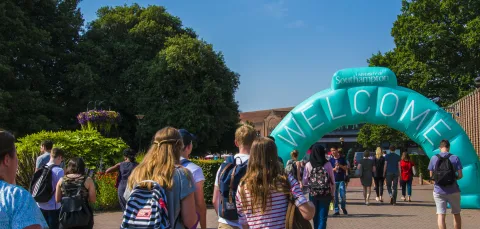 Open Day visitors walking through a large, blue welcome archway at Highfield Campus