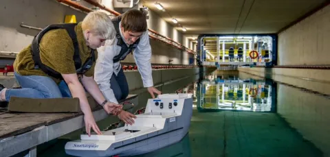 Two students test a model boat in the towing tank