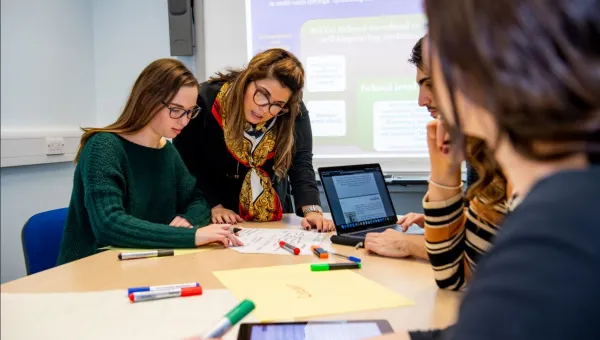 Education students taking part in small group learning using laptops and marker pens