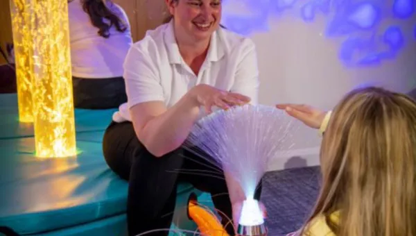 A healthcare student works with a child in a multisensory room