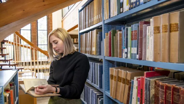 A student browsing by a bookshelf in Hartley Library