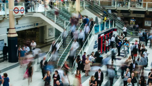 Many people in train station with stairs.