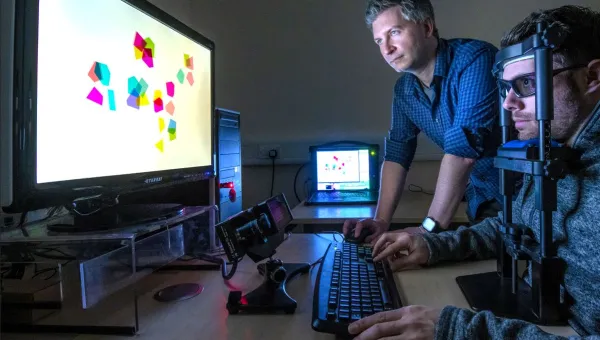 A psychology researcher observes a particpant in an eye tracking experiment