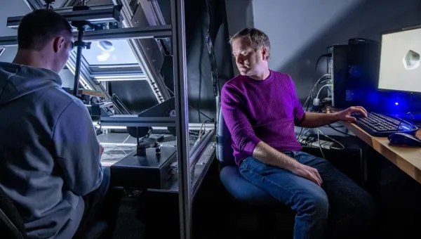 A researcher observes a participant using haptic feedback equipment