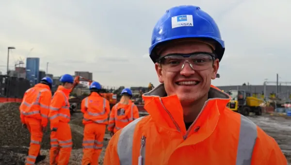 A group of engineering students in overalls and hard hats in an industrial setting