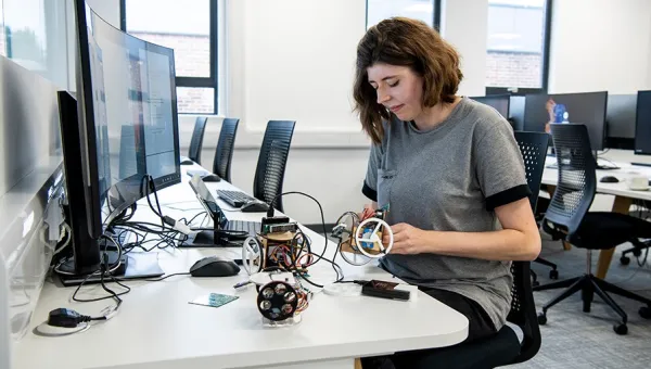 A researcher at a desk with computers and electronic equipment