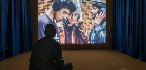 A young man watching an audio-visual art piece at the John Hansard art gallery.
