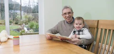 Michael Knowlton, the first person in the world to test a vaccine for his type of head and neck cancer, reading a book with his granddaughter.