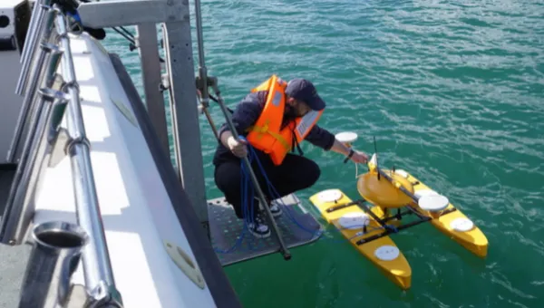 A Southampton Geospatial researcher on a boat prepares a device for collecting data in Studland Bay