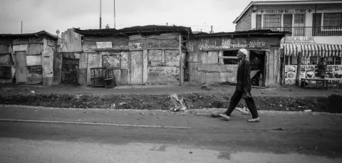 A black and white image of an elderly gentleman walking past a row of businesses in Nairobi, Kenya.