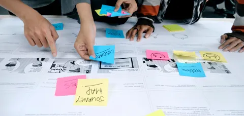Several pairs of hands posting sticky notes on hand drawn designs