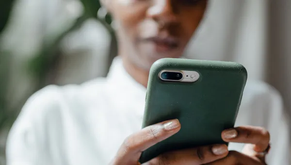 Pexels image of a person clasping a mobile phone intently looking at screen