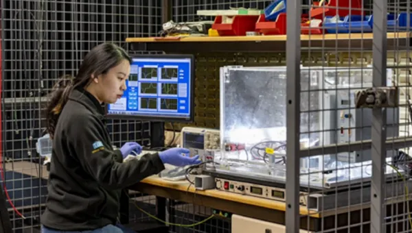 Researcher sitting at a work bench changing equipment settings