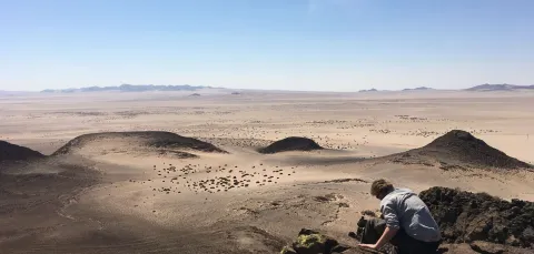 Man on top of rocks overlooking a desert