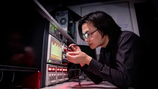 Researcher testing an integrated circuit attached to a computer and display screens