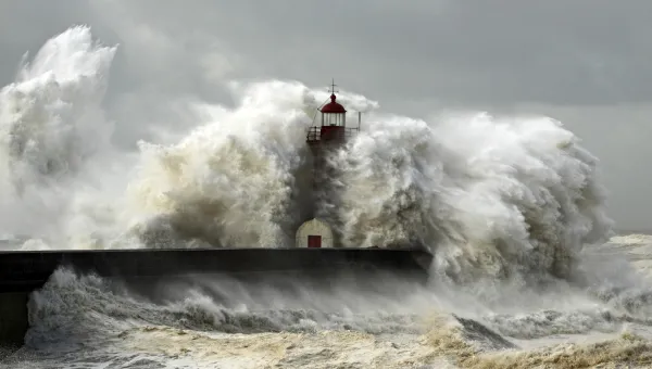 Large waves crash against a lighthouse during a storm surge, an unusual rise in sealevel