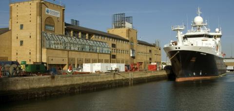 The long quayside frontage of the National Oceanography Centre, as seen from the water. A large research vessel sits on the water.