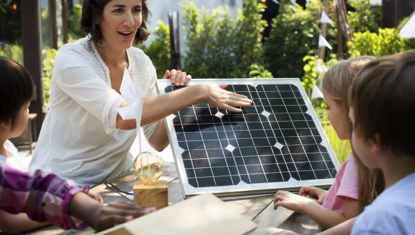 A female teacher showing her pupils a solar panel