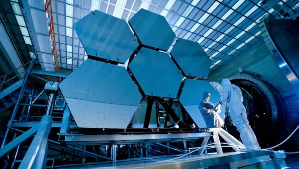 A technician testing hexagonal solar panels for a satellite