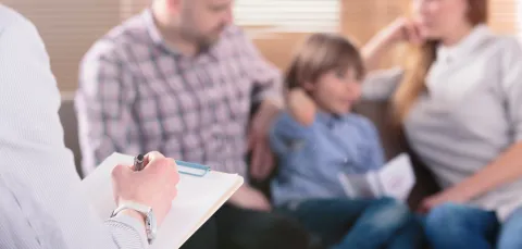 A therapist take notes while interviewing a family