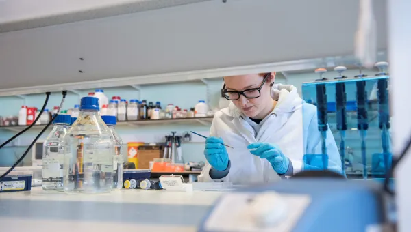A researcher in a lab, examining a slide
