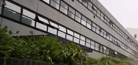 Close-up of a long, 3 storey concrete and glass building