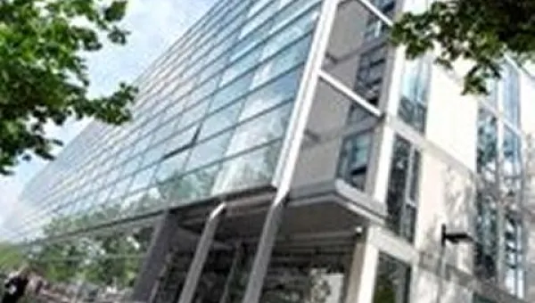 With the leaves of trees in the foreground, filling the frame is a contemporary, glass-filled building viewed from street level, the 'EEE' building on Highfield Campus