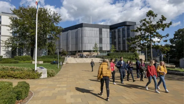 Students walk on a sunny campus with modern buildings and greenery