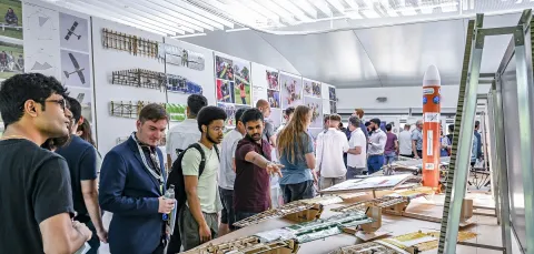 A group of students admire work on display at the annual engineering design show