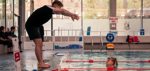 An instructor demonstrating a stroke to a student in the pool