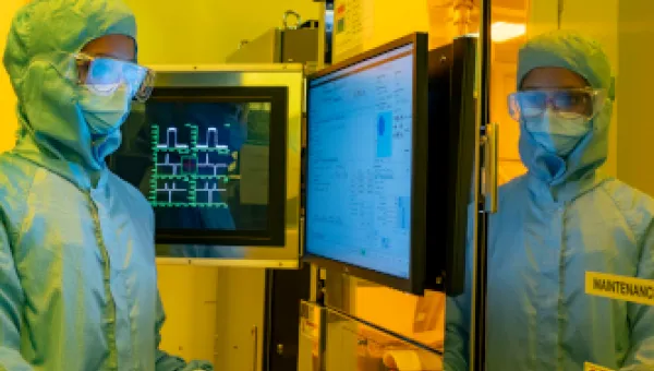 A researcher in a cleanroom suit and wearing a protective glasses, uses the electron beam lithography (EBL) facility