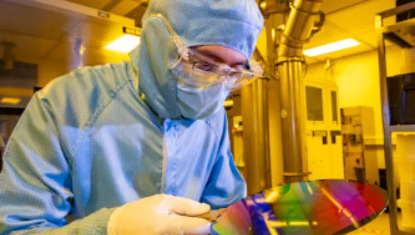 A researcher in a cleanroom suit with a 200mm wafer in the nanofabrication cleanroom