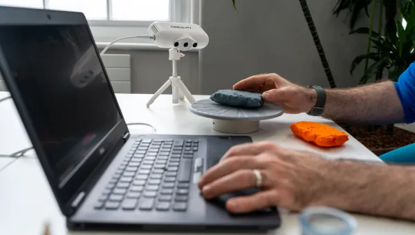 Open laptop on a desk with an unseen user, bar their wrists, operating the keyboard.