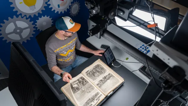A person is shown using scanning equipment to scan a historic document