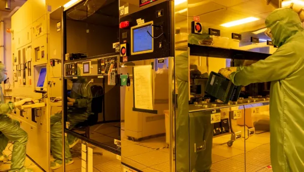 Two men working within projection lithography facility equipment