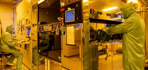 Two men working within projection lithography facility equipment