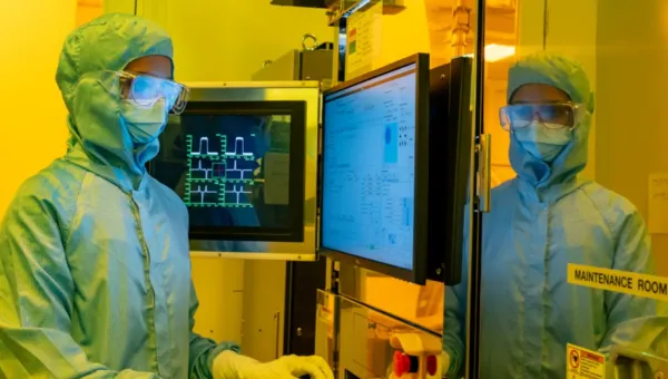 A woman standing in front of electron beam lithography tool control
