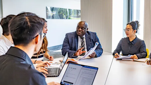 Professor Ven Tauringana and students dicussing at table