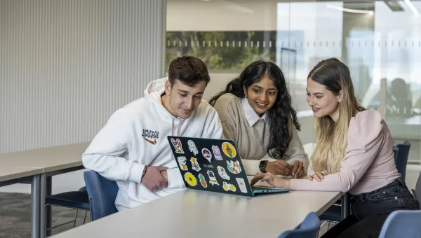 Three students with a laptop