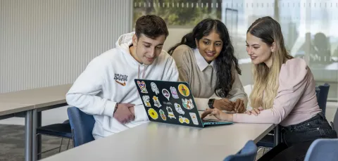 Three students with a laptop