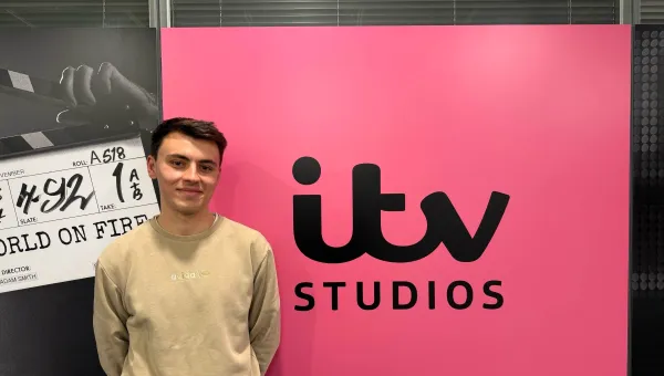 BA Spanish and Linguistics Graduate, Joe Dobinson standing by a sign for ITV studios.